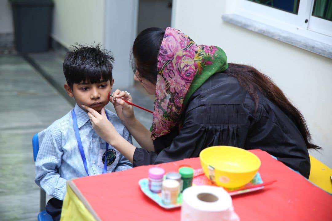 A teacher painting a child’s face on activity day